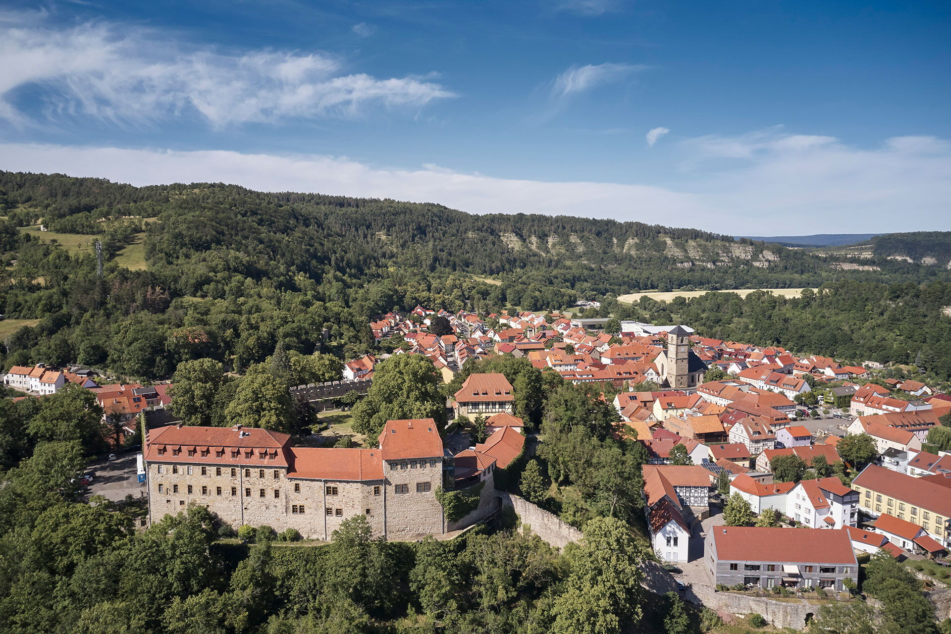 Blick auf Creuzburg mit der gleichnamigen Burg aus der Vogelperspektive - im Hintergrund sind die markanten Felsen der Ebenauer Köpfe im Werratal zu sehen